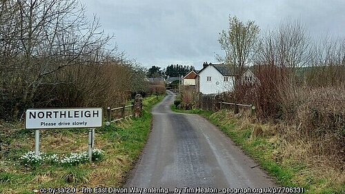 A road entering the village of Northleigh with a sign reading "Northleigh" on the left