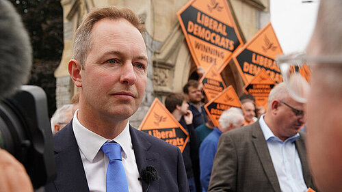 Richard Foord being interviewed in front of activists and signs reading "Liberal Democrats Winning here"