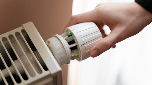 Person adjusting a radiator thermostat