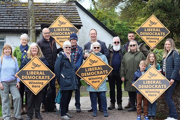 Richard Foord stood with a group of smiling volunteers who are holding Liberal Democrat posters