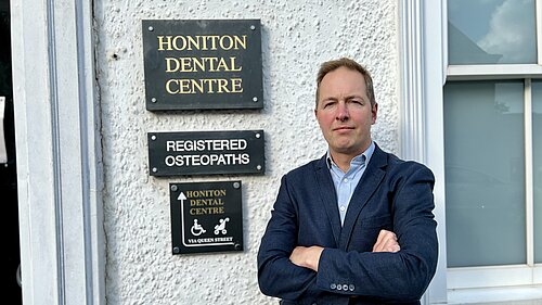 Richard Foord standing in frnt of the sign for Honiton Dental Centre