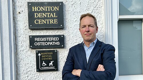 Richard Foord standing in frnt of the sign for Honiton Dental Centre