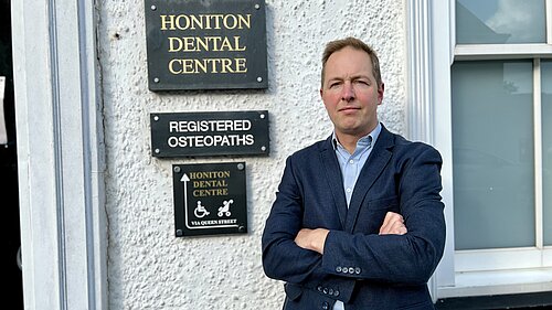 Richard Foord standing in frnt of the sign for Honiton Dental Centre