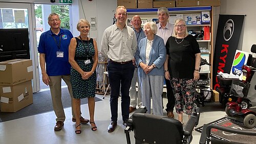 Richard Foord standing with a group of people in the showroom for TRIP Honiton. There are two to his right, and four on the left, with a motorised wheelchair in front of them