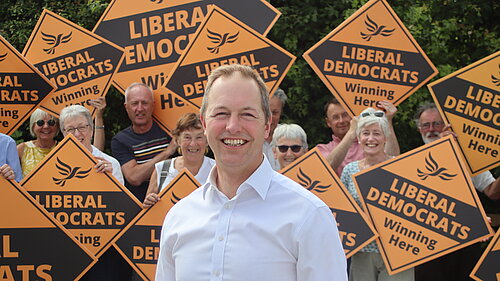 Richard Foord stood in front of a wall of volunteers holding Liberal Democrat diamonds