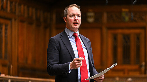 Richard Foord standing in Parliament speaking and looking toward the government benches